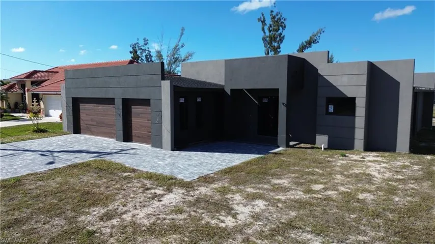 Contemporary home featuring stucco siding, an attached garage, and decorative driveway