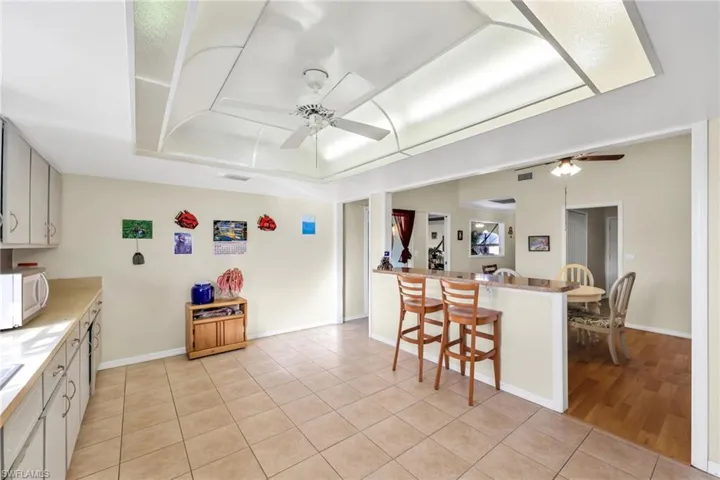 Kitchen featuring a breakfast bar area, light countertops, light tile patterned floors, and a tray ceiling