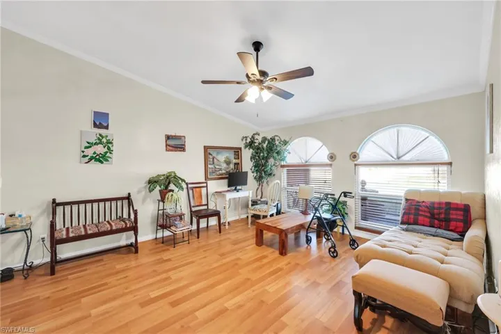 Living area with ornamental molding, light wood-type flooring, a ceiling fan, and vaulted ceiling