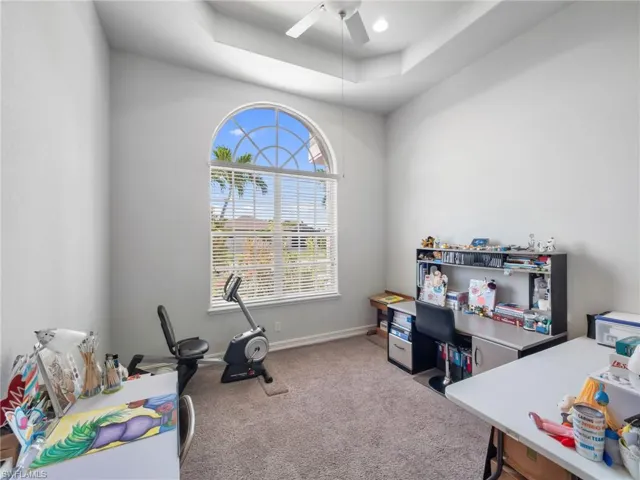 Carpeted office with ceiling fan and a raised ceiling
