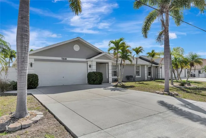 Ranch-style home with stucco siding, an attached garage, driveway, and a front lawn