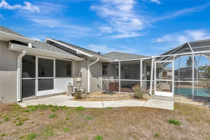 Back of property with a sunroom, roof with shingles, and a lanai