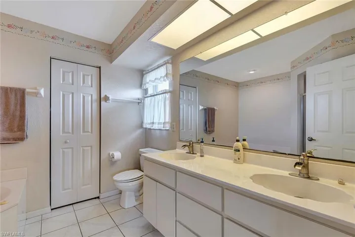 Full bath featuring double vanity, a closet, and light tile patterned flooring