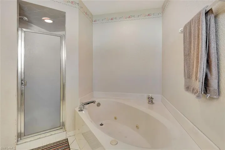 Bathroom with a shower stall, a tub with jets, and light tile patterned floors