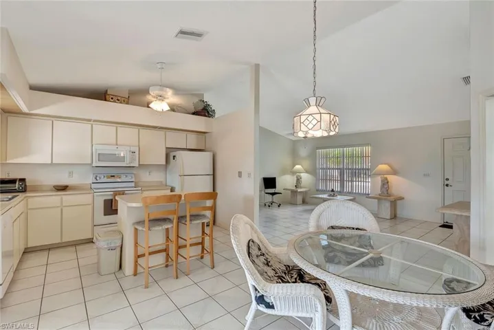 Kitchen featuring white appliances, light countertops, open floor plan, a breakfast bar area, and lofted ceiling