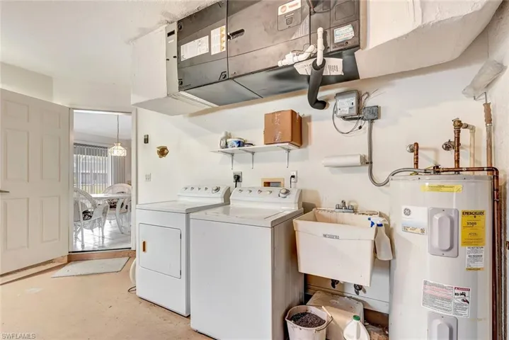 Laundry area featuring electric water heater, washing machine and clothes dryer, and concrete flooring