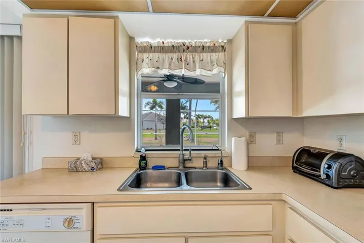Kitchen with dishwasher, light countertops, and cream cabinets