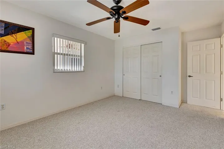 Unfurnished bedroom featuring a closet, light carpet, and a ceiling fan