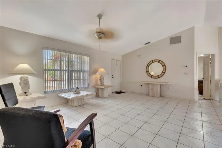 Living area featuring lofted ceiling, light tile patterned floors, and a ceiling fan