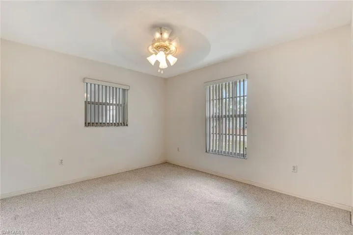 Carpeted spare room featuring a ceiling fan and baseboards