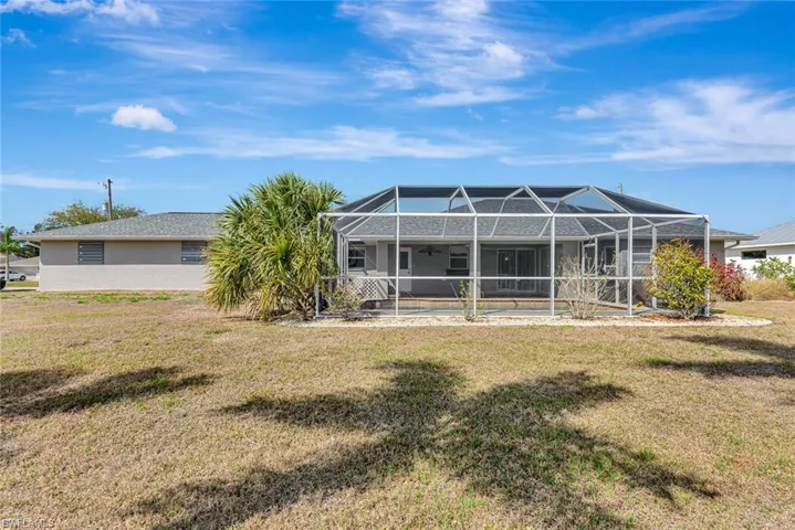 Back of house featuring a sunroom, a lanai, a pool, and a yard