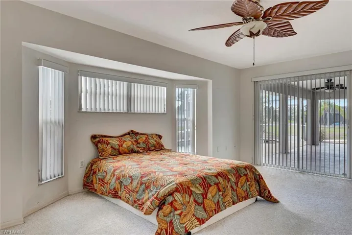 Carpeted bedroom with access to outside, multiple windows, and a ceiling fan