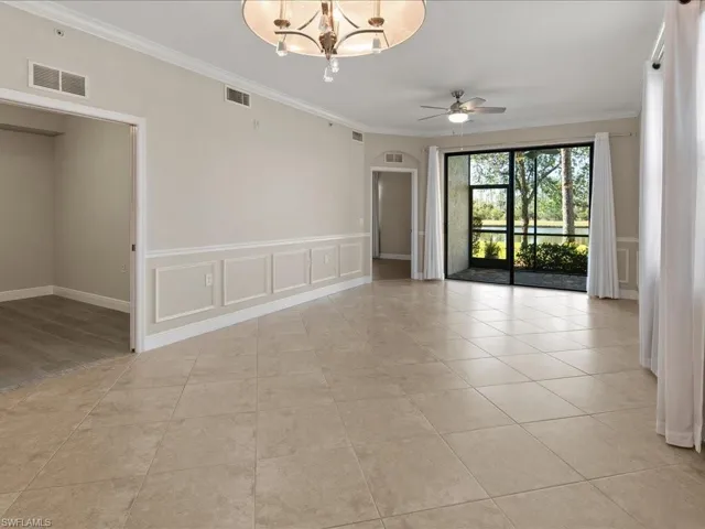 Unfurnished room featuring a decorative wall, wainscoting, crown molding, a ceiling fan, and a chandelier