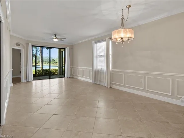 Empty room with a wainscoted wall, a ceiling fan, crown molding, a water view, and a decorative wall
