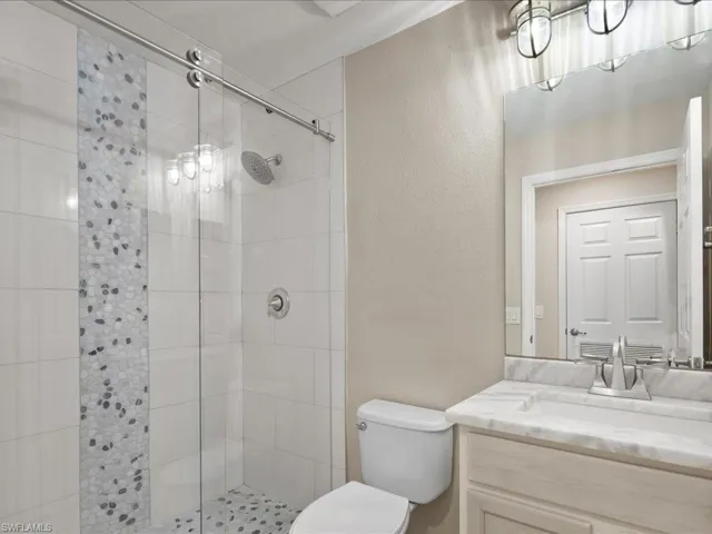 Bathroom featuring a textured wall, a shower stall, and vanity