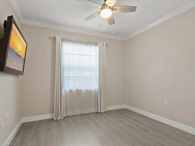 Spare room featuring wood finish floors, ceiling fan, and ornamental molding