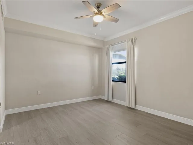 Empty room featuring light wood-style floors, ornamental molding, and ceiling fan