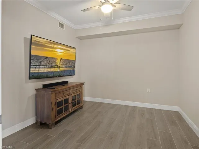 Unfurnished room with wood finish floors, a ceiling fan, and crown molding