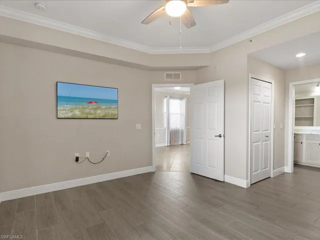 Unfurnished bedroom with crown molding, wood finished floors, ceiling fan, and ensuite bath
