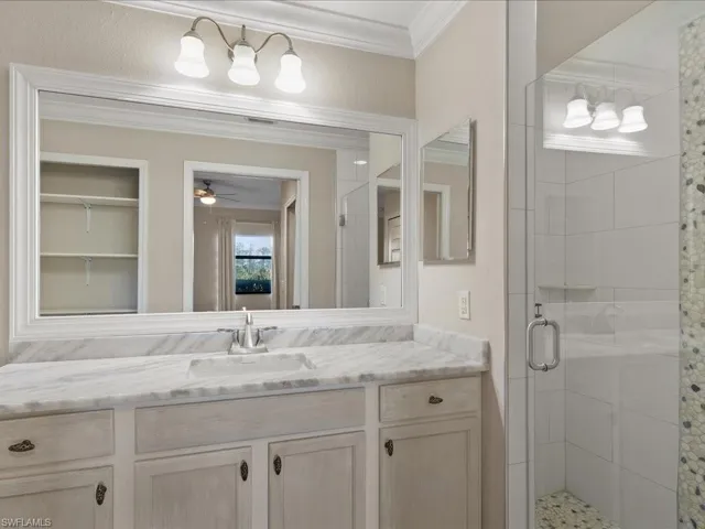 Full bath with a shower stall, vanity, ornamental molding, and ceiling fan