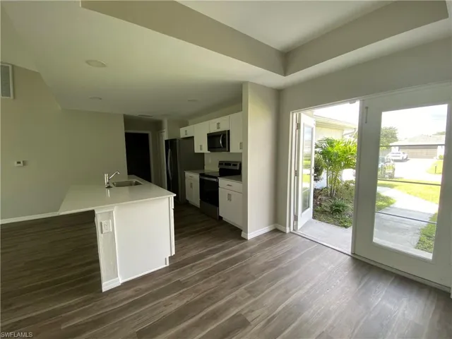 Kitchen with white cabinets, appliances with stainless steel finishes, and dark wood-style flooring