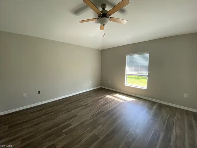 Unfurnished room featuring dark wood-style flooring and ceiling fan