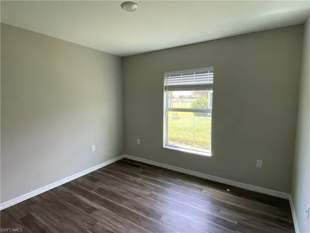 Unfurnished room with baseboards and dark wood finished floors