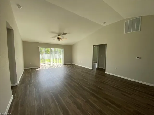 Spare room featuring dark wood-type flooring, a ceiling fan, and vaulted ceiling
