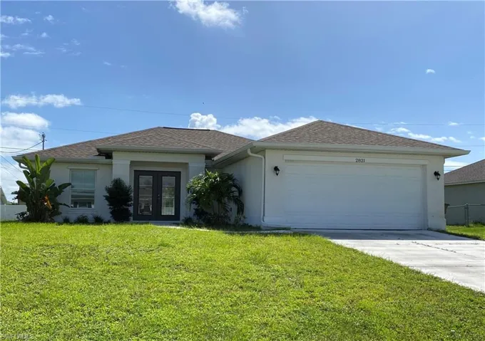 Ranch-style home featuring stucco siding, a front yard, driveway, and a garage
