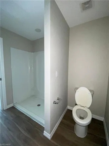 Bathroom with dark wood-style flooring and a stall shower