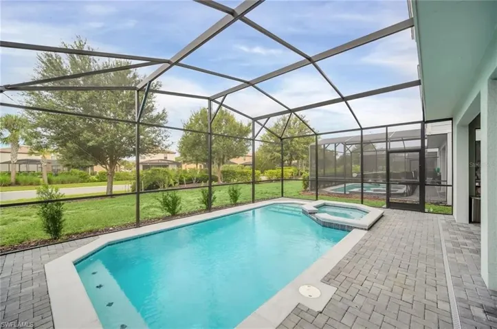 Relaxing pool / spa with glass enclosure, a sunroom, a yard, and a patio area