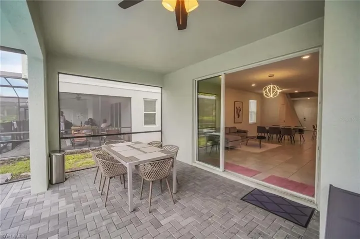 Sunroom featuring outdoor dining space, ceiling fan, and a patio area