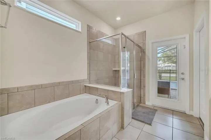 Bathroom featuring a stall shower, a garden tub, and light tile patterned floors