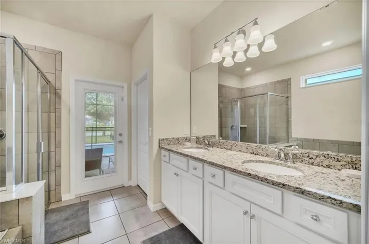 Full bathroom with double vanity, healthy amount of natural light, a shower stall, and light tile patterned floors