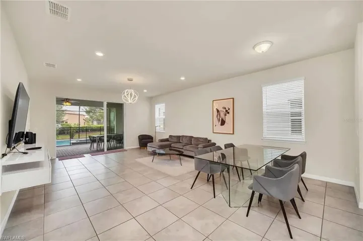 Living room with plenty of natural light, light tile patterned floors, suspended lighting, and ceiling fan