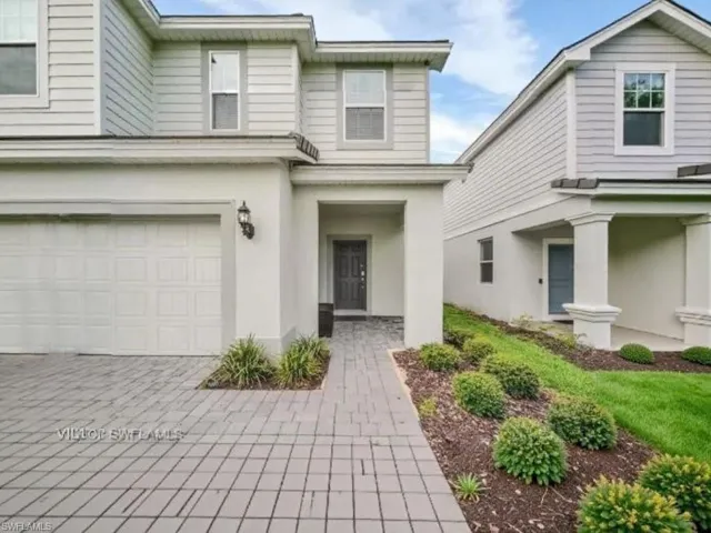 View of front facade featuring stucco siding, a garage, and driveway
