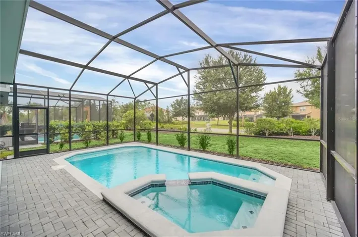 Integrated pool / spa featuring a sunroom, a patio, glass enclosure, and a lawn