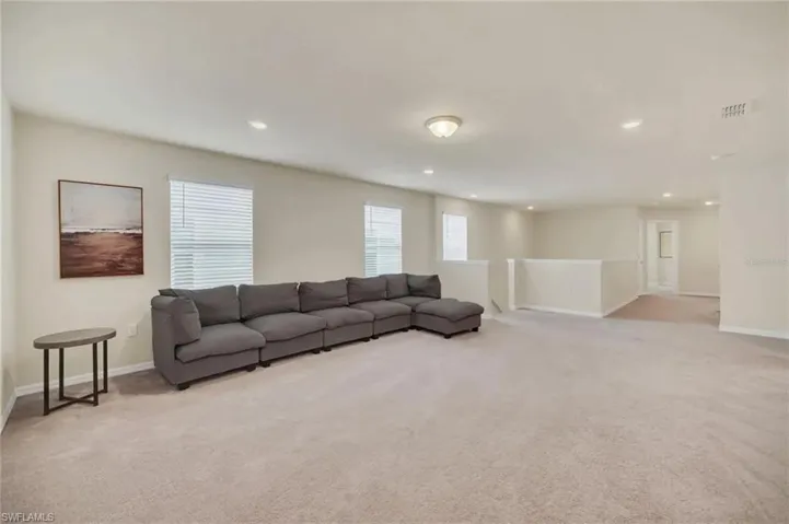Living area featuring light colored carpet and recessed lighting