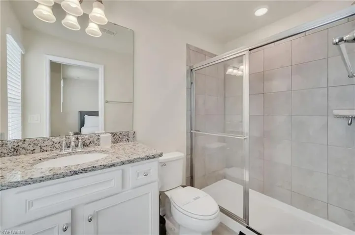 Bathroom with vanity, a stall shower, and suspended lighting