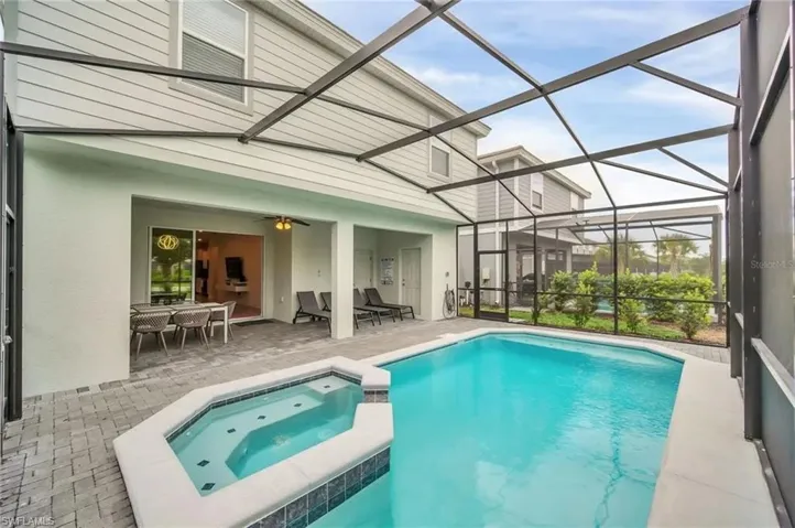 Relaxing pool / spa with a sunroom, a patio, a lanai, and outdoor dining area