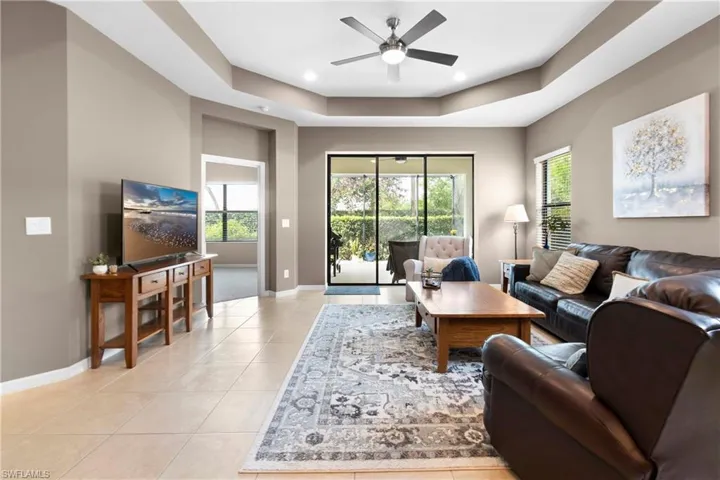 Living area featuring a healthy amount of sunlight, light tile patterned floors, baseboards, and a raised ceiling