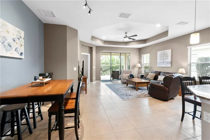 Living room with a tray ceiling, light tile patterned flooring, and a ceiling fan