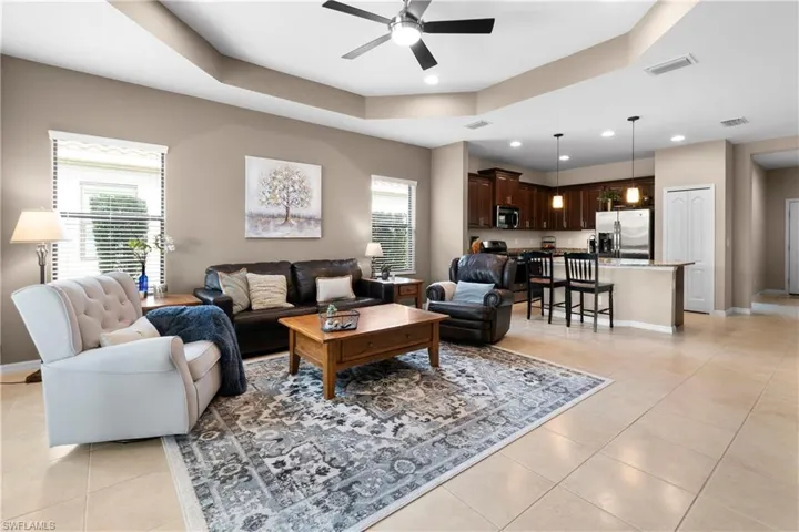 Living room with light tile patterned floors, a raised ceiling, visible vents, and baseboards
