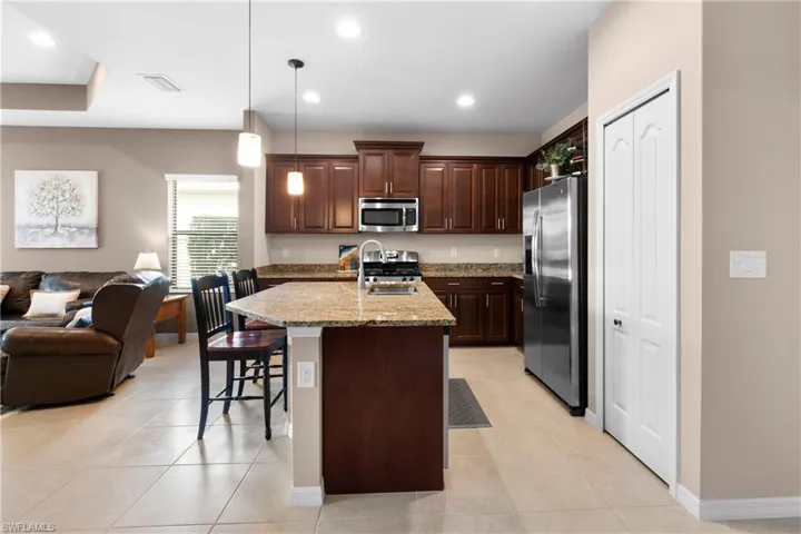 Kitchen featuring an island, open floor plan, hanging light fixtures, appliances with stainless steel finishes, and an island with sink