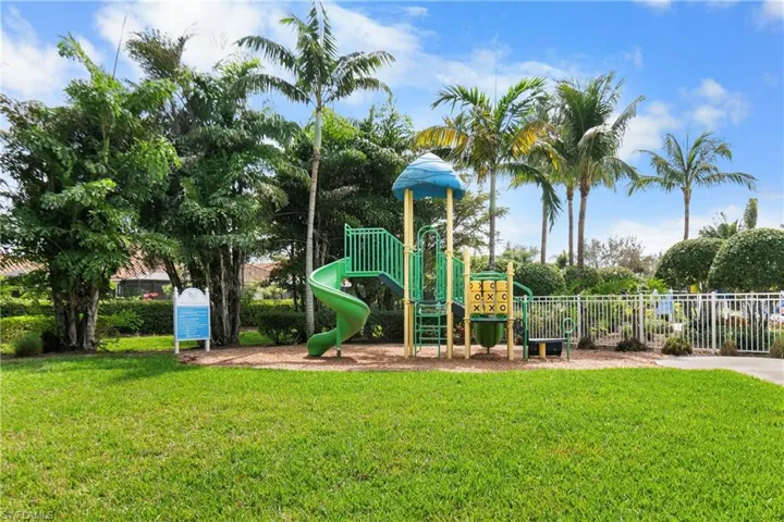 Communal playground featuring fence and a lawn