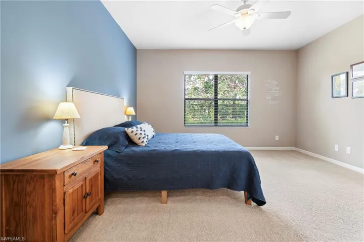 Bedroom with a ceiling fan, light carpet, and baseboards