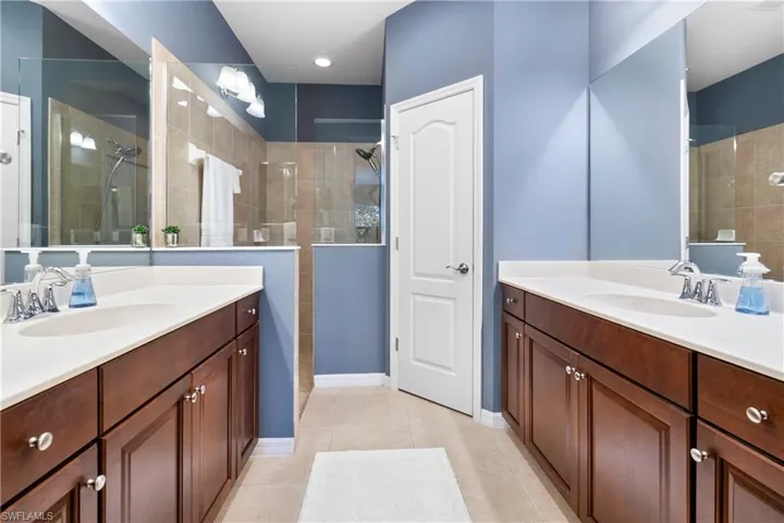 Full bath with a walk in shower, two vanities, a sink, and tile patterned floors