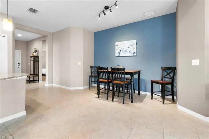 Dining room with light tile patterned floors, rail lighting, visible vents, and baseboards