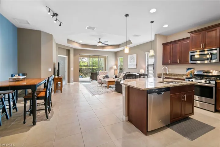 Kitchen featuring stainless steel appliances, a sink, open floor plan, light stone countertops, and pendant lighting
