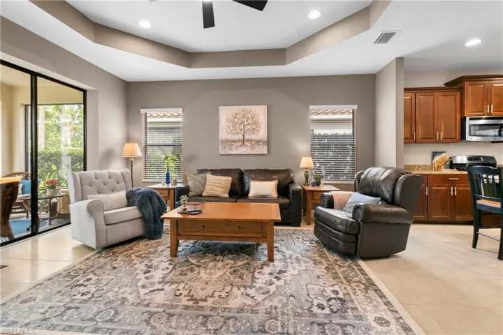 Living room featuring a tray ceiling, light tile patterned floors, recessed lighting, visible vents, and ceiling fan